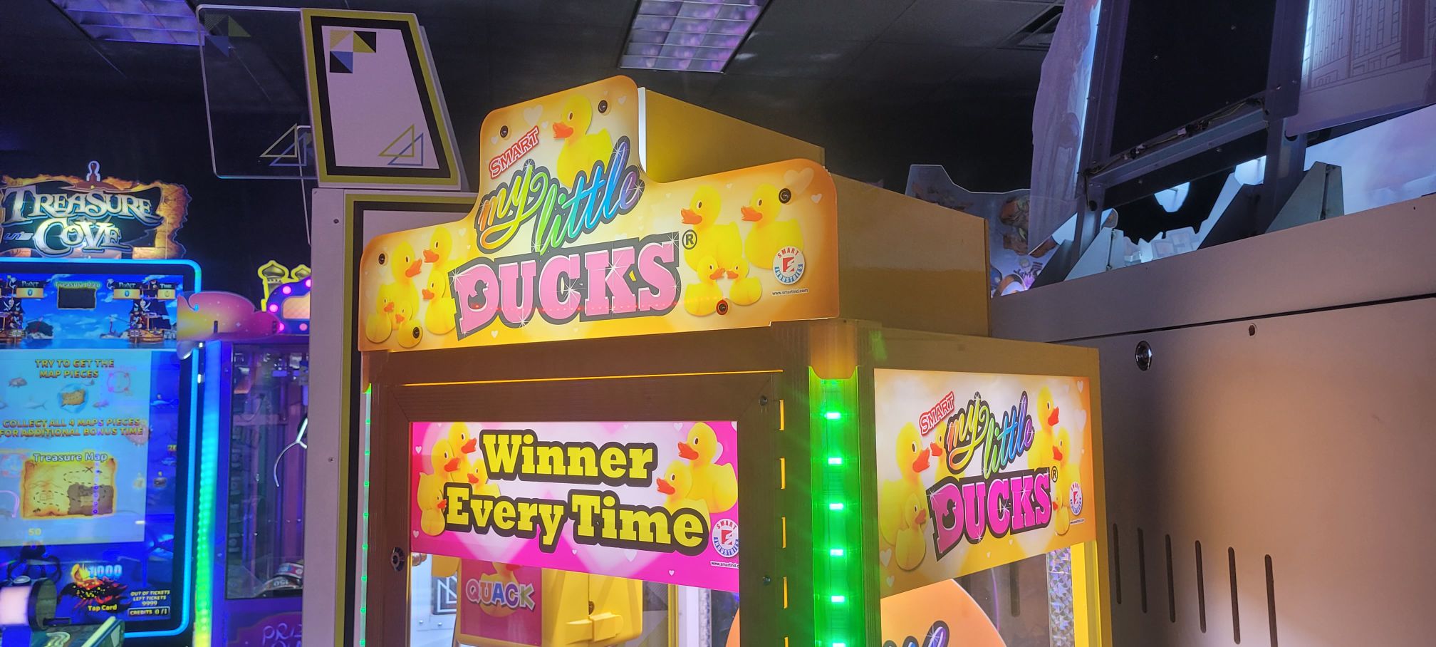 A brightly lit My Little Ducks arcade crane game machine.