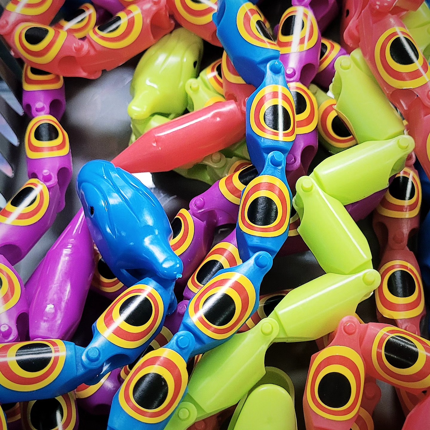 A close-up pile of interconnected plastic snake fidget toys in vibrant neon colors.