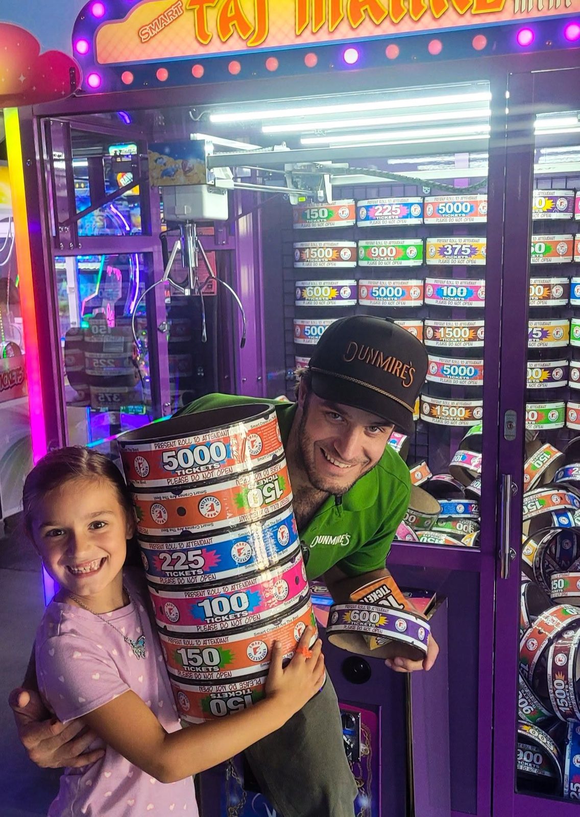 A dad and daughter hold a tall stack of ticket rings