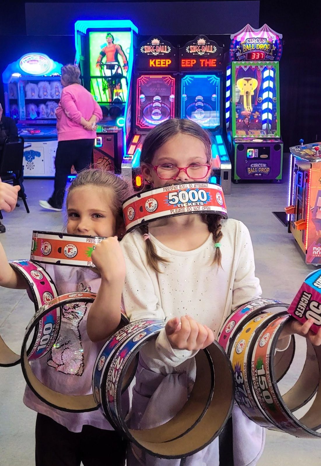 Two girls hold up a 5000-ticket ring and stacks of tickets