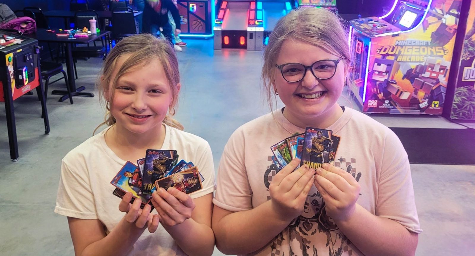 Two girls show off fans of Avengers trading cards they won