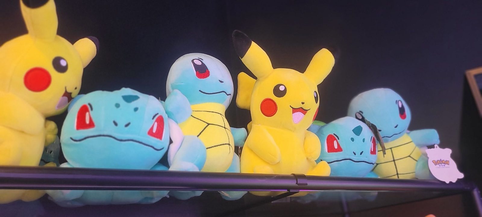 A row of Pikachu, Squirtle, and Bulbasaur plush prizes