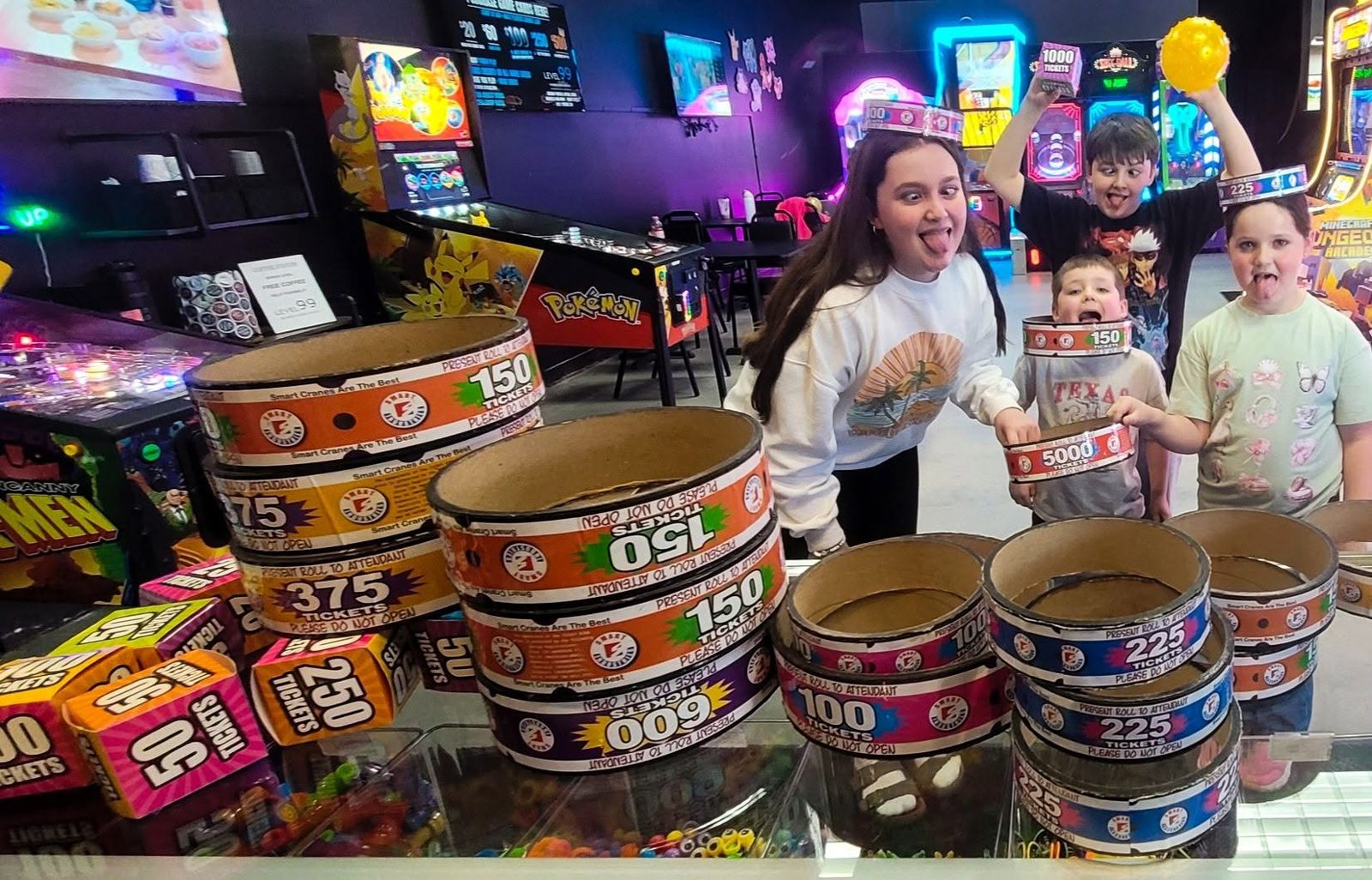 Kids cheer behind a counter piled high with ticket buckets